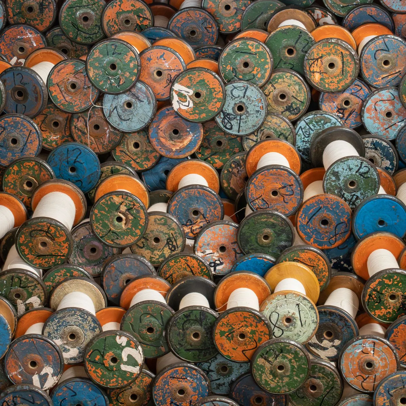 Industrielle Garnspulen in Blau, Grün und Orange, dicht gestapelt