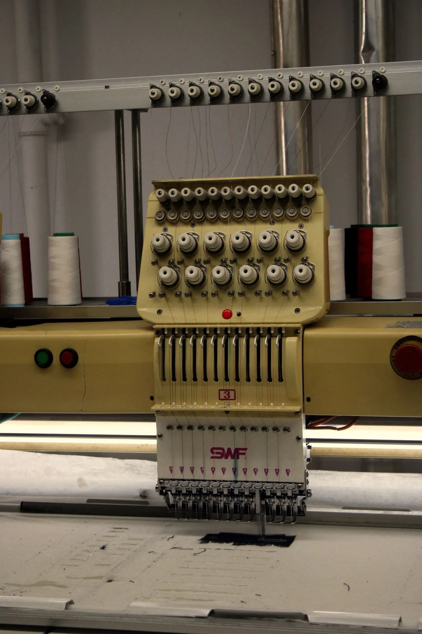Stickmaschine mit Garnrollen und eingefädelten Nadeln